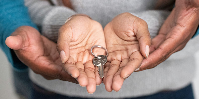 Man and woman holding house key in open hands.